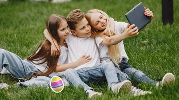 Drei Kinder machen Selfie auf Rasen.