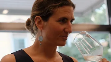 Frau riecht Wein im Glas drinnen.