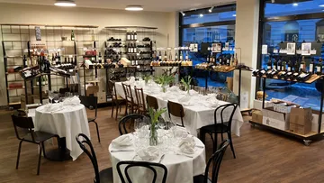 Wine shop with dining tables and shelves.
