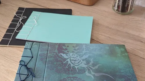 Drei dekorative Notizbücher auf Holztisch.