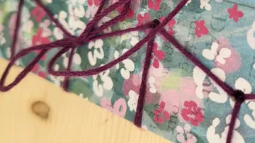 Gefädelter Faden auf Blumenpapier gebunden.