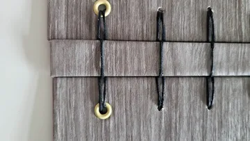 Beige curtain with black string ties.