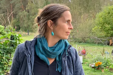 Woman looking sideways, outdoor garden setting.