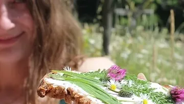 Woman holding bread with flowers outdoors.