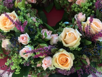 Blumenkranz aus Rosen und Grün, präsent auf rotem Hintergrund.