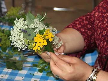 Eine Hand hält einen bunten Blumenstrauß in einer Werkstatt.