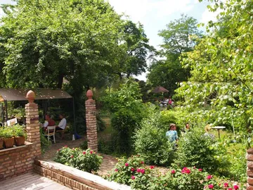 Grüner Garten mit Menschen, die entspannt im Freien sitzen.
