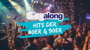 Menschenmenge bei Konzert mit Konfetti und Lichtern.