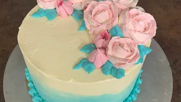 Kuchen mit rosa Blumen und blauen Blättern.