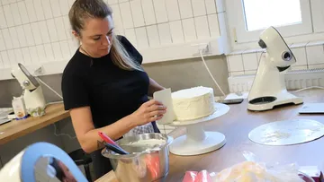 Frau dekoriert Kuchen in Küche.
