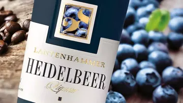 Bottle of liqueur next to blueberries and coffee beans.