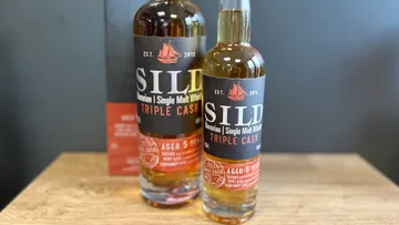 Two whiskey bottles on a wooden surface.