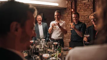 Gruppe genießt Getränke in einer Backsteinbar.