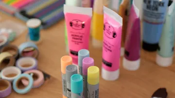 Acrylfarben und Marker auf Tisch.