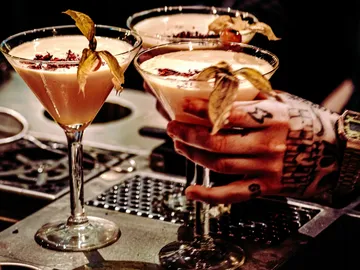 Cocktails on a table are held by one hand.