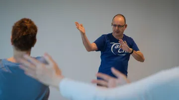 Mann leitet Tai Chi-Unterricht drinnen.