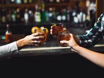Gläser mit Getränken werden von Händen erhoben, bar.