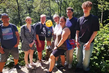 Group of seven people posing in forest.