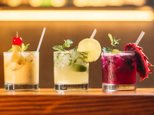 Three colorful cocktails stand on a wooden trunk.