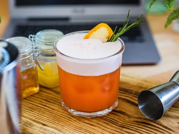 Cocktail with foam and citrus on a table.