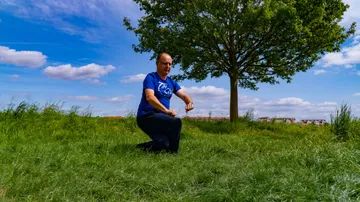 Man practicing Tai Chi on grassy field.