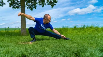 Man stretching in a grassy field.