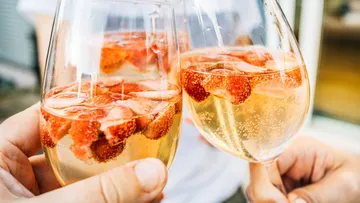 Two glasses with strawberries and bubbly drink.