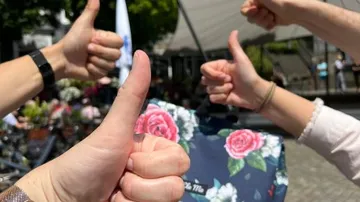 Vier Hände zeigen Daumen hoch im Freien.