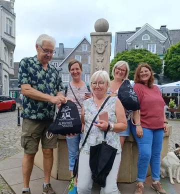 Gruppe posiert mit Taschen nahe einem Brunnen.