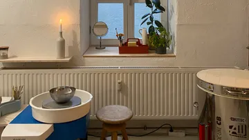 Töpferstudio mit Töpferscheibe und Brennofen.