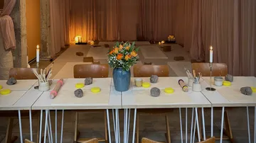 Basteltisch mit Ton und Blumen, gedämpftes Licht.