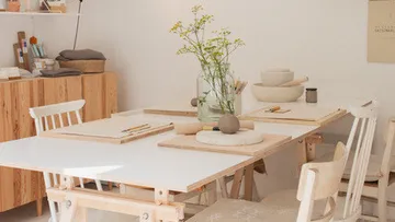 Tisch mit Töpferwerkzeug und Blumen im Studio.