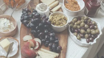 Charcuterie board with fruits, cheese, and olives.