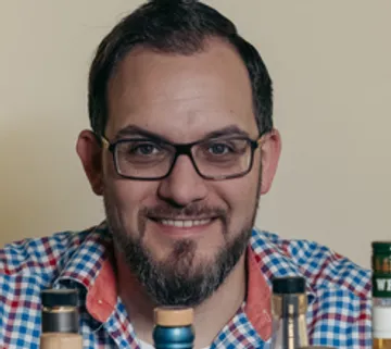 Lächelnder Mann mit Flaschen vorne, drinnen.