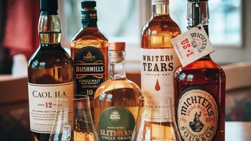 Fünf Whiskyflaschen auf einem Tisch drinnen.