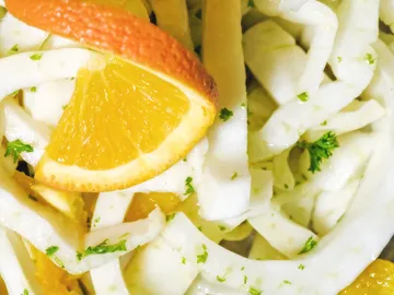 Wurstscheiben mit Orangenscheiben und grüner Petersilie dekoriert.
