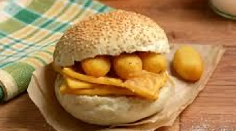 Bread roll filled with fried food on table.