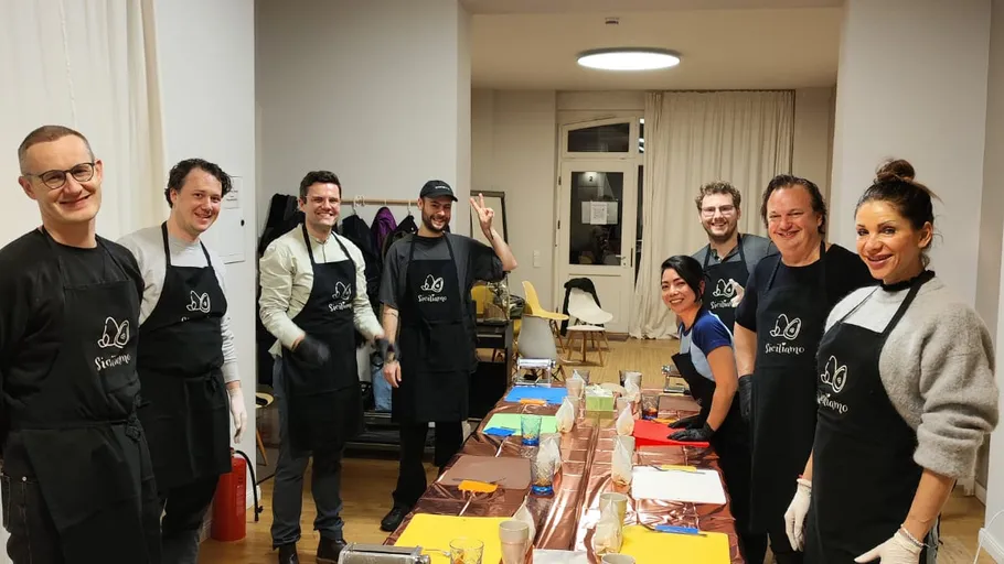 Group of people wearing aprons in kitchen.