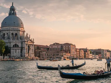 Venezianische Gondeln fahren vor historischer Architektur im Wasser.