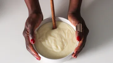 Hands holding bowl of thick porridge.