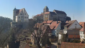 Burg und Häuser in einem Dorf auf dem Hügel.