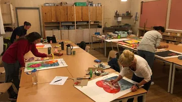 Personen malen in einem gut beleuchteten Kunstraum.