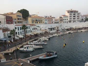 Harbour with boats, people strolling in picturesque surroundings.