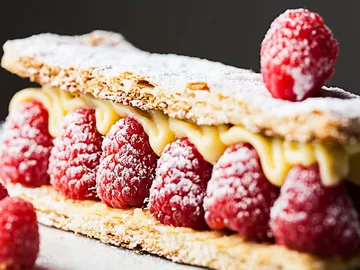 Raspberry pie with pudding on puff pastry, decorated with powdered sugar.