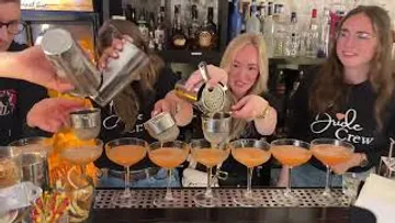 Group preparing cocktails in a bar.