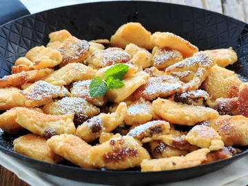 Pastries on a black plate, sprinkled with powdered sugar.