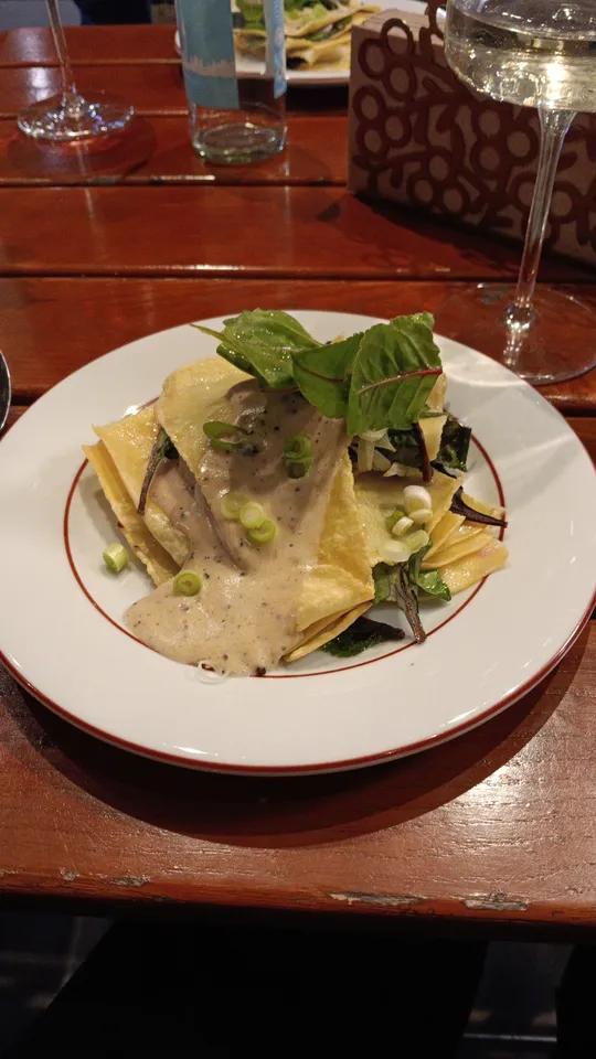 Pasta with cream sauce and greens on plate.