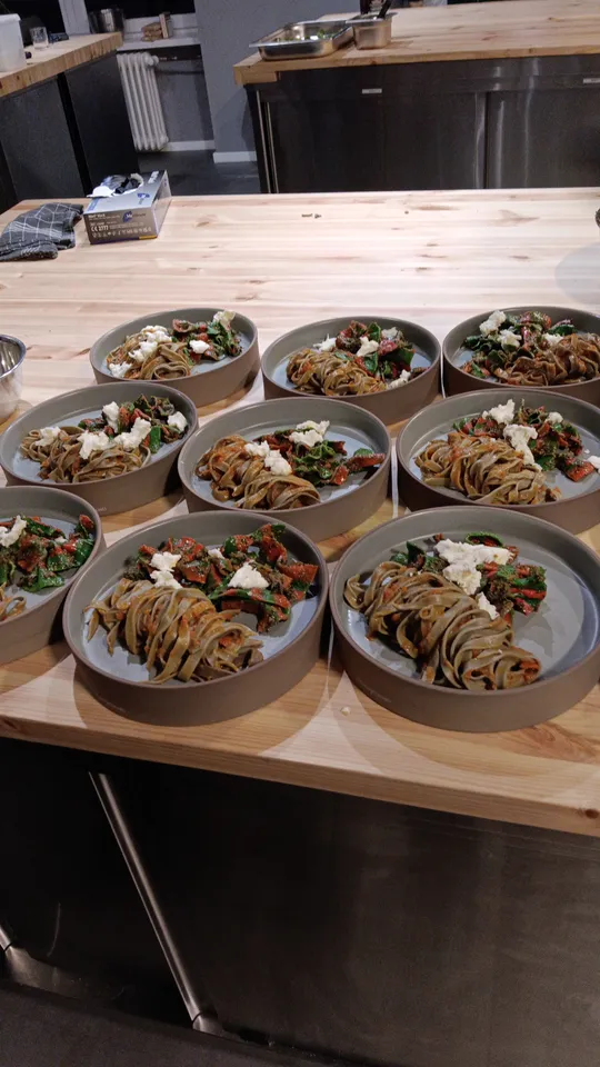Plates of pasta with vegetables on wooden table.