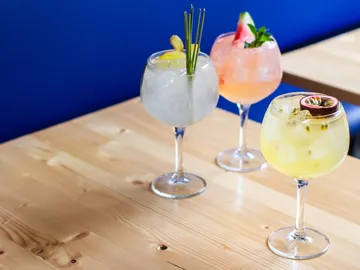 There are three cocktails on a wooden table.
