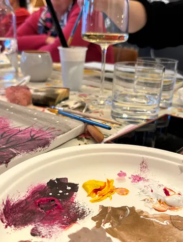 Paint palette and drinks on table.